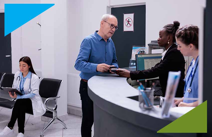Bank customer receiving assistance at front desk while staff coordinate technology and operations.