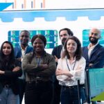 Diverse cybersecurity team standing confidently in a financial operations center, representing VFINDIT’s cybersecurity staffing for banks and data protection services.