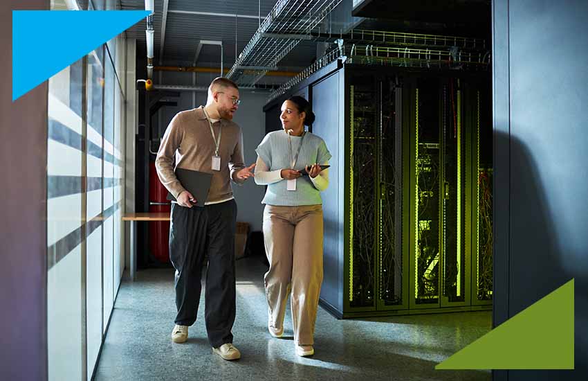 Two IT consultants discussing system operations while walking through a data center, representing insurance domain technology consulting.
